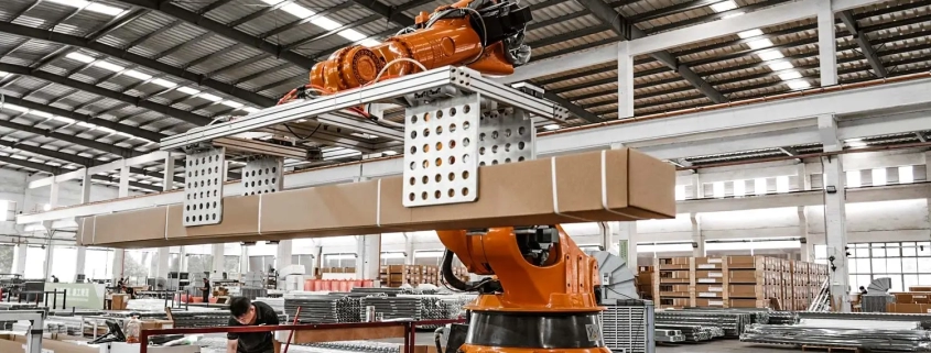 Robotic arm lifting packaged boxes from conveyor in modern pergola factory