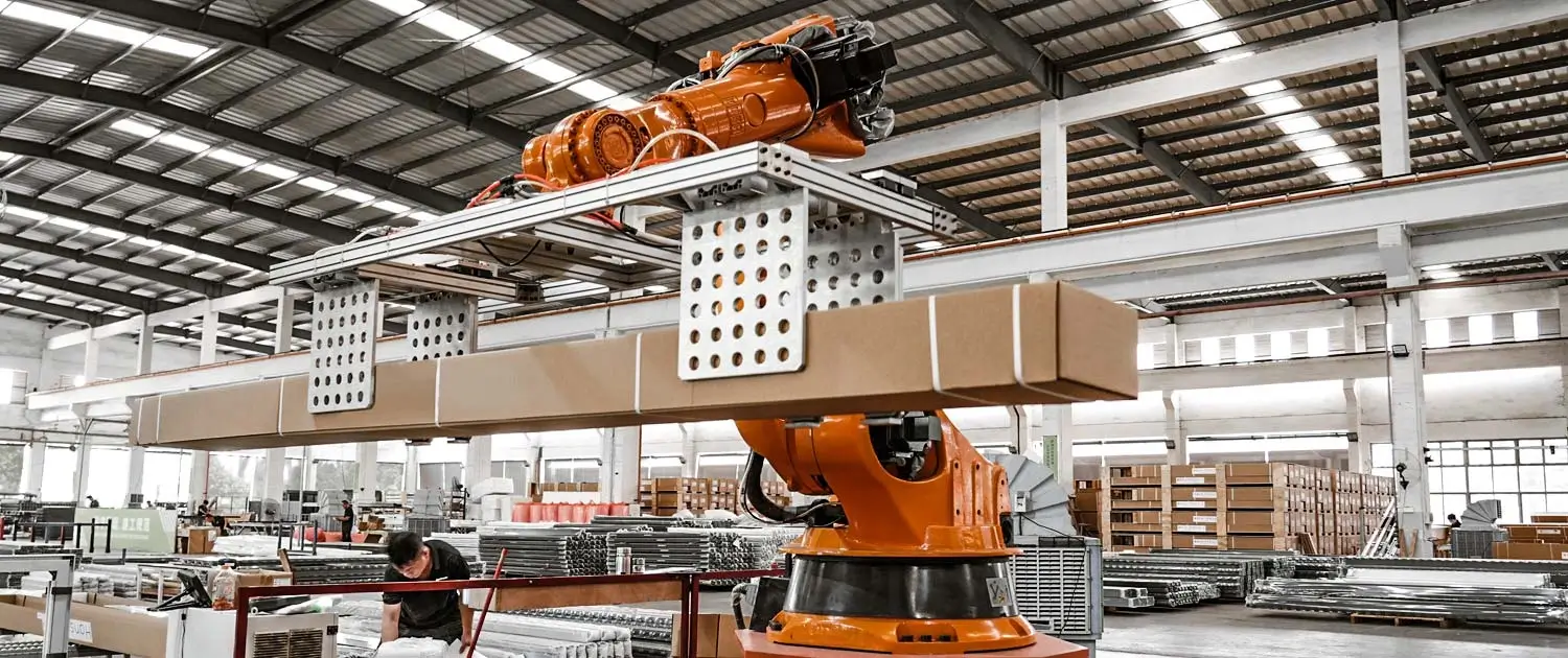 Robotic arm lifting packaged boxes from conveyor in modern pergola factory
